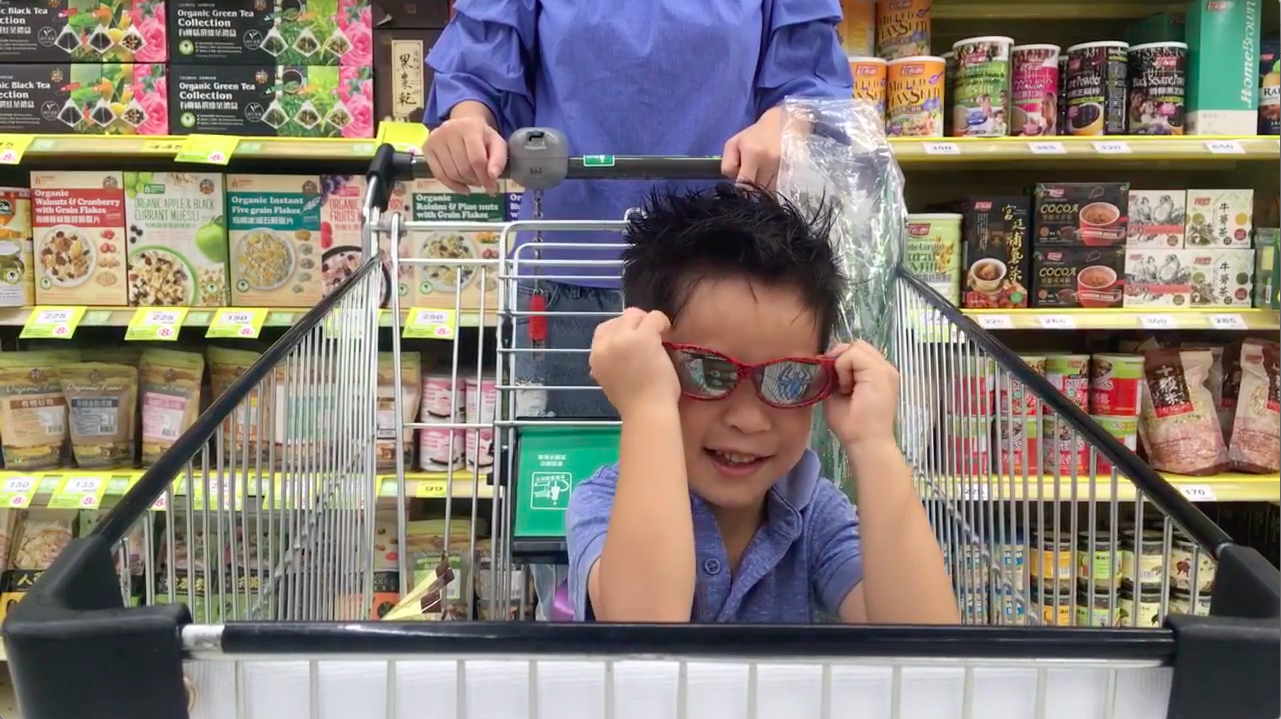 一個小孩坐在購物車裡戴著墨鏡好神氣