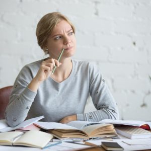 穿著灰色衣服的女子歪著頭表現出煩惱的樣子