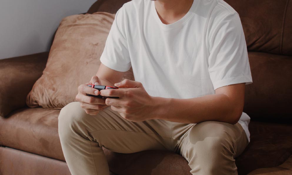 白色衣服卡其色褲子的男子坐在沙發上打電動