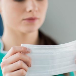 穿著綠色衣服女生拿著口罩戴口罩