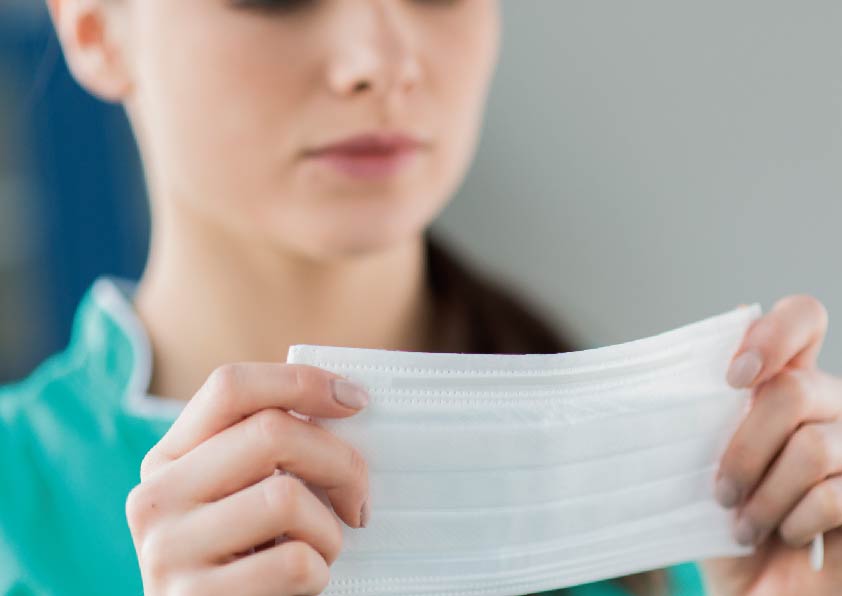 穿著綠色衣服女生拿著口罩戴口罩